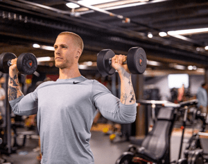 male using dumb bells in a gym setting at qntm fit life