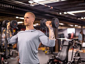 male using dumb bells in a gym setting at qntm fit life